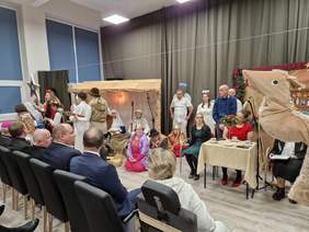 Widać liczną grupę wykonawców w strojach, oraz część widowni