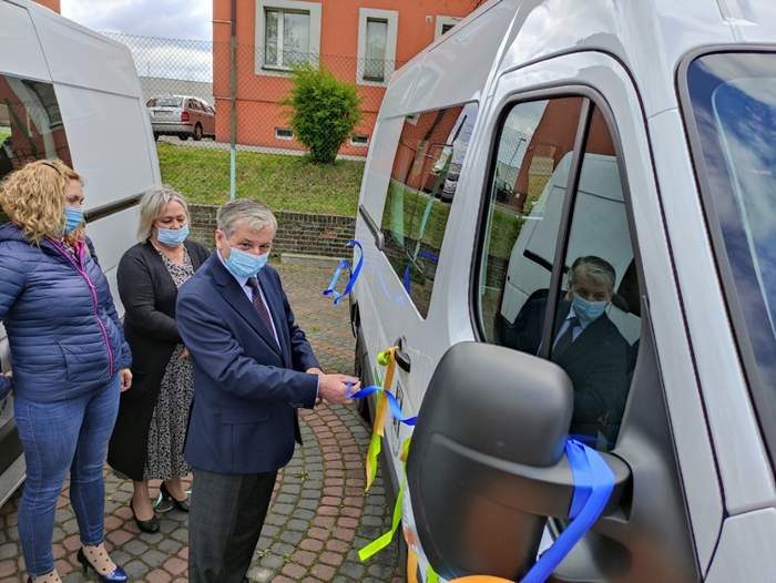 Pokaż zdjęcie: Między białymi busami stoją dwie kobiety i mężczyzna który przeciął wstążkę na jednym z pojazdów