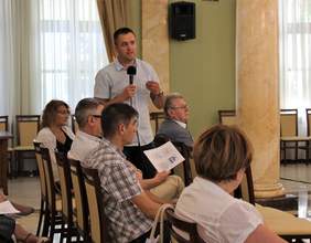 Pokaż zdjęcie: Uczestnik spotkania z mikrofonem udziela się w dyskusji