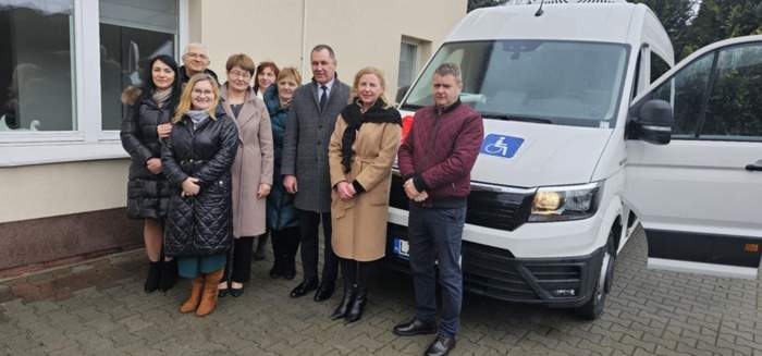 Pokaż zdjęcie: Na tle białego busa do pamiątkowej fotografii ustawili się zaproszeni goście.