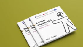 Trzy egzemplarze publikacji „Kompas Dostępności” ułożone na zielonym tle. Na okładce widnieje tytuł publikacji, grafika symbolizująca dostępność oraz logotypy UKE i PFRON.
