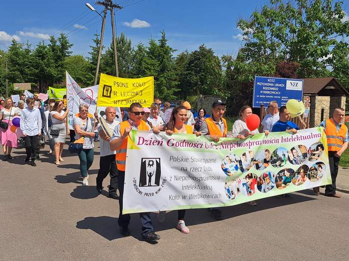 Pokaż zdjęcie: Początek Marszu Godności, na przodzie kilka osób trzyma transparent z hasłem: Dzień Godności Osób z Niepełnosprawnością Intelektualną. 