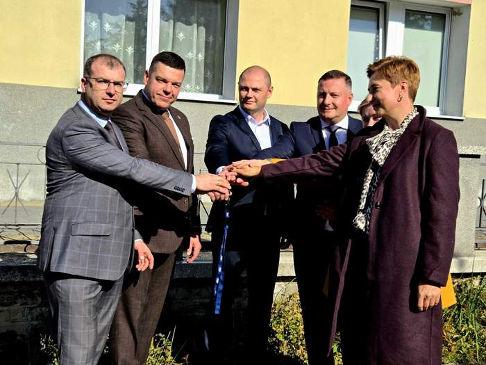 Pokaż zdjęcie: Dwie kobiety i czterech mężczyzn trzyma się kluczyków w uroczystym geście przekazania.