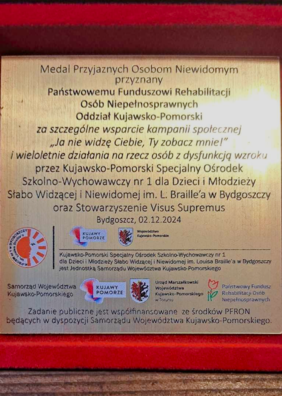 Wygrawerowana tabliczka, umieszczona w pudełku, w którym znajduje się medal