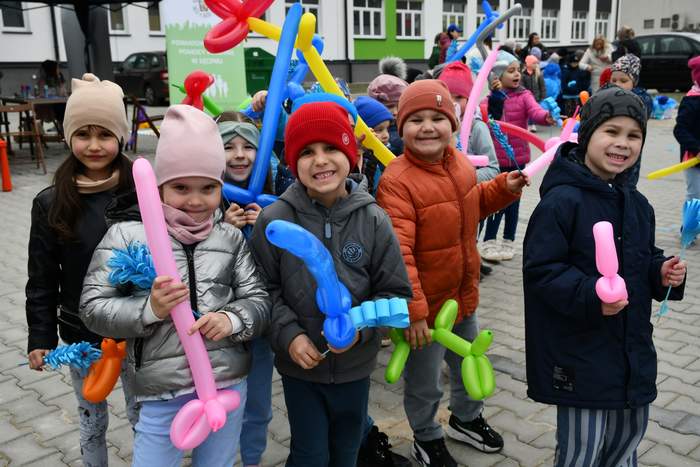 Pokaż zdjęcie: Zdjęcie na zewnątrz podczas festynu, przedszkolaków trzymających w ręku kolorowe balony.