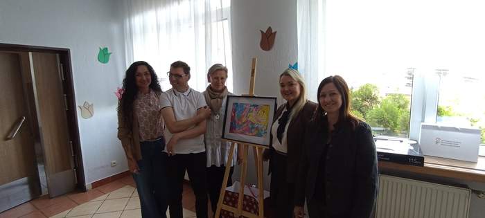 Pokaż zdjęcie: 3 kobiety wraz z Krzysztofem Górnym stoją na tle nagrodzonej pracy