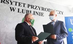 Pokaż zdjęcie: Prezes Zarządu PFRON Krzysztof Michałkiewicz i Rektor UP w Lublinie prof. dr hab. Krzysztof Kowalczyk stoją na tle ściany z napisem UP w Lublinie, trzymają teczki z podpisanym tekstem Porozumienia