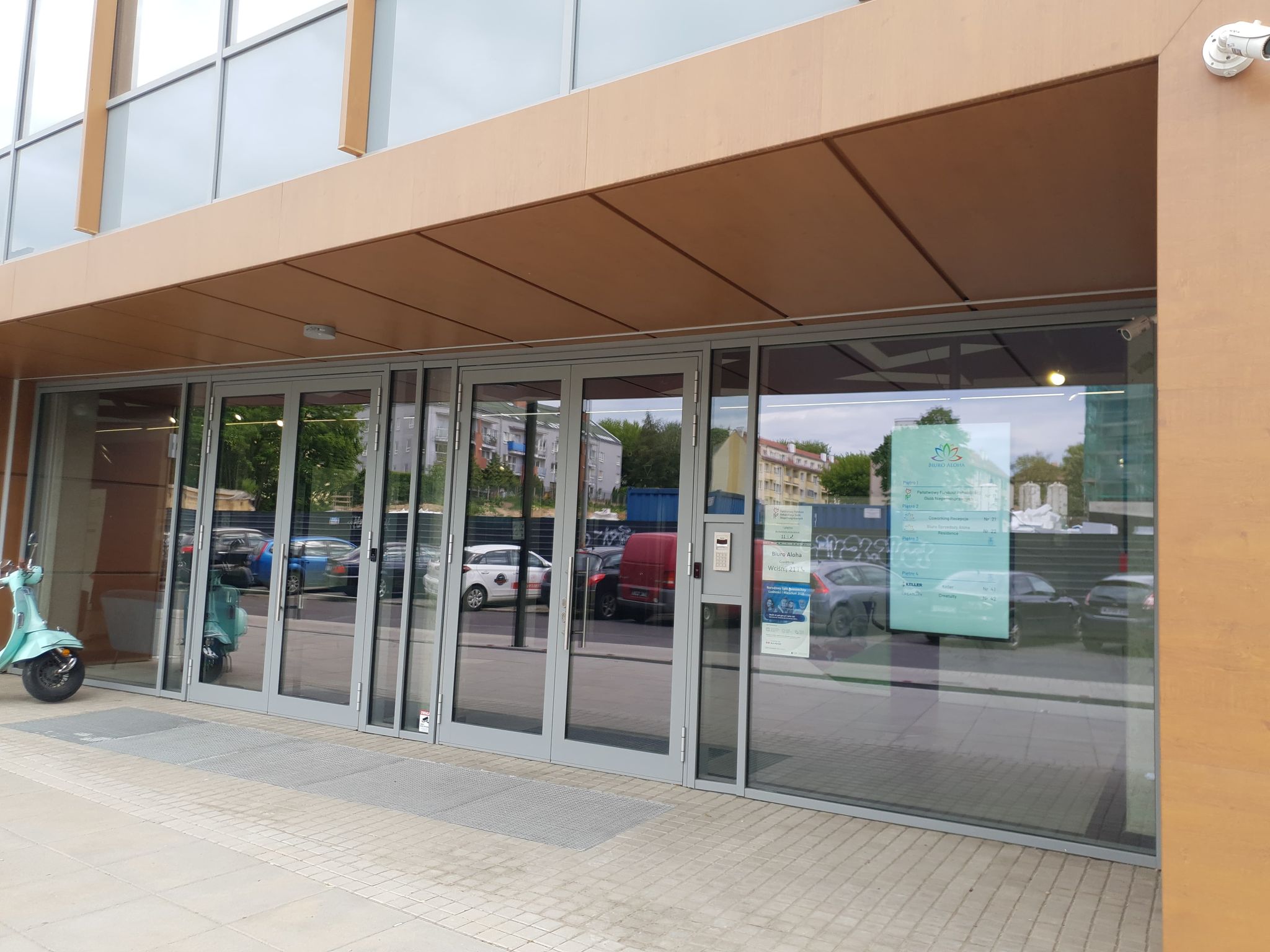 Wejście do budynku Wejście do budynku, w którym mieści się siedziba Zachodniopomorskiego Oddziału PFRON. 2 pary dwuskrzydłowych przeszklonych drzwi prowadzą do środka. Na prawo od nich domofon, a po jego prawej stronie tablice informacyjne instytucji mieszczących się w budynku.